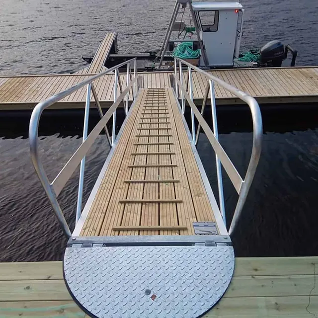 Landgang med tredekke leder til flytebrygge med arbeidsbåt fortøyd.