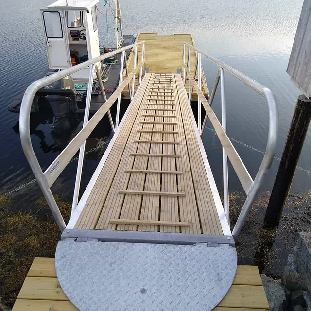 Utsikt ned landgang fra kai til flytebrygge med båt ved siden av.